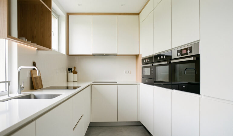 Cuisine moderne bien organisée avec rangements intégrés, plan de travail épuré et équipements harmonieux, éclairage naturel doux.